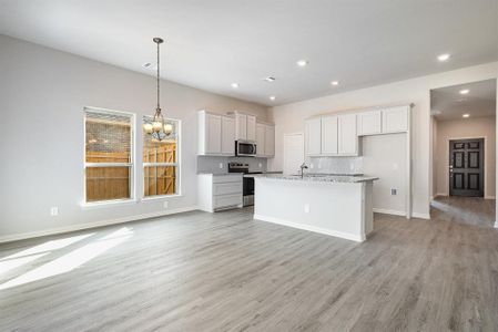 Kitchen featuring white cabinets, light stone countertops, appliances with stainless steel finishes, and light hardwood / wood-style flooring