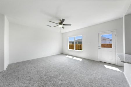 Carpeted living room featuring ceiling fan and a wealth of natural light