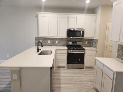 Kitchen featuring white cabinetry, backsplash, light hardwood / wood-style floors, appliances with stainless steel finishes, and sink