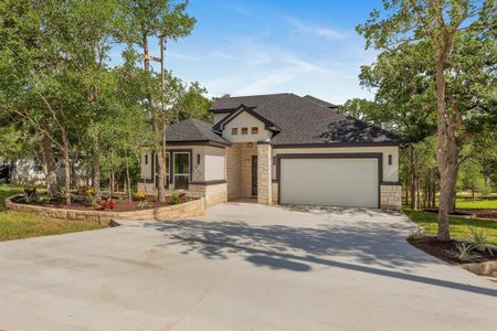 View of front of property featuring stone siding, stucco siding, driveway, and a garage