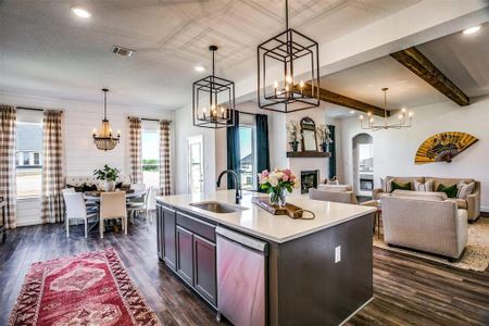 Kitchen with a center island with sink, stainless steel dishwasher, sink, and hanging light fixtures