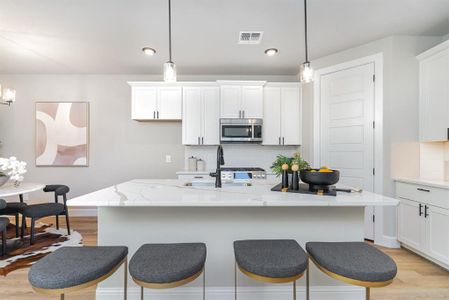 Kitchen featuring pendant lighting, backsplash, sink, and an island with sink