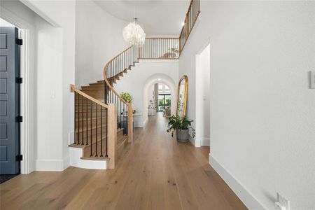 Foyer entrance with wood-type flooring, a towering ceiling, and an inviting chandelier