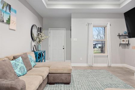 Living room with crown molding, a tray ceiling, and light hardwood / wood-style floors