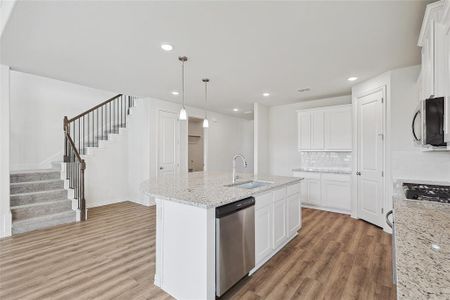 Kitchen with appliances with stainless steel finishes, light hardwood / wood-style flooring, white cabinets, sink, and backsplash