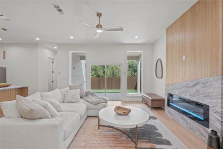 Living room with light wood-type flooring, ceiling fan, and wood walls