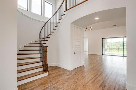 Stairway with a notable chandelier, a high ceiling, and hardwood / wood-style flooring