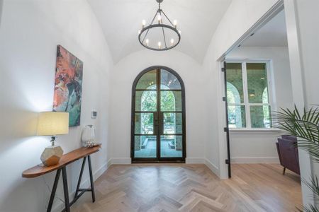 Entrance foyer featuring french doors, vaulted ceiling, a notable chandelier, and light parquet flooring