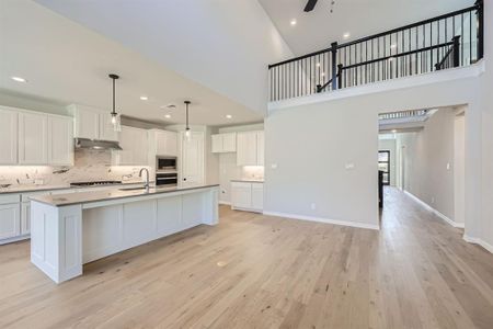 Kitchen featuring light wood-type flooring, a kitchen island with sink, stainless steel appliances, and white cabinets