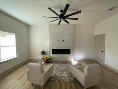 Living room with ceiling fan, light hardwood / wood-style floors, and a fireplace