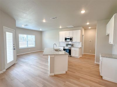 Kitchen featuring stainless steel appliances, white cabinetry, sink, light wood-type flooring, and light stone countertops