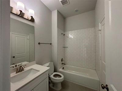 Full bathroom with vanity, toilet, tile patterned flooring, and tiled shower / bath