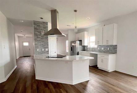 Kitchen with island exhaust hood, pendant lighting, dark wood-type flooring, stainless steel fridge with ice dispenser, and white cabinetry