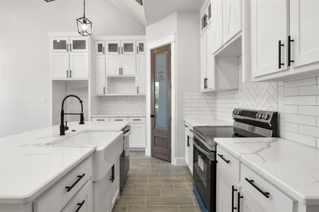 Kitchen featuring light stone counters, white cabinets, hanging light fixtures, a center island with sink, and stainless steel range with electric stovetop