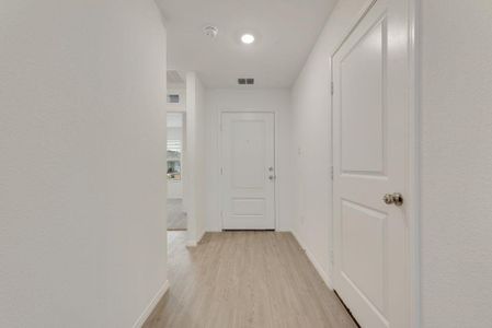 Hallway featuring light wood finished floors, visible vents, and baseboards