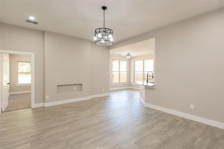 Unfurnished living room with light hardwood / wood-style floors and a chandelier