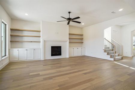 Unfurnished living room with a fireplace, light hardwood / wood-style flooring, and ceiling fan