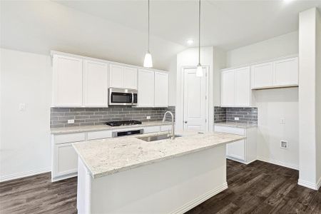 Kitchen with white cabinets, appliances with stainless steel finishes, an island with sink, and sink