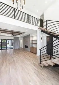 Staircase with ceiling fan, a fireplace, light hardwood / wood-style flooring, and a high ceiling