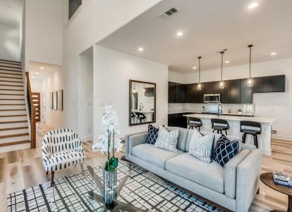 Living room featuring a high ceiling, sink, and light hardwood / wood-style flooring