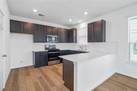 This spacious kitchen features large windows, high ceilings, stained wood cabinets, silestone countertops, SS appliances, modern tile backsplash, recessed lighting, and pantry all overlooking your huge family room.