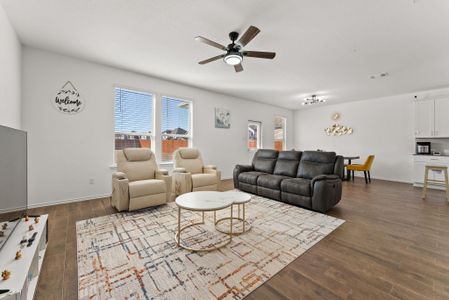 Living area featuring dark wood-style floors, ceiling fan, visible vents, and baseboards