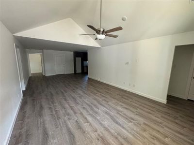 Unfurnished living room with hardwood / wood-style flooring, lofted ceiling, and ceiling fan