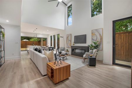 Living room with a high ceiling, ceiling fan, and light hardwood / wood-style floors