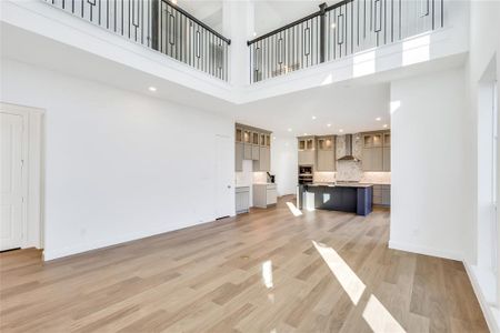 Unfurnished living room with a towering ceiling and light wood-type flooring