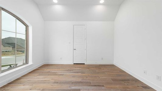 Unfurnished room with light hardwood / wood-style flooring and vaulted ceiling