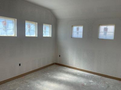 Spare room with a wealth of natural light, lofted ceiling, and baseboards