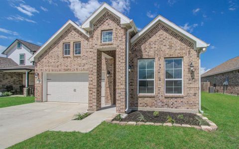 This is a modern single-family brick home featuring a high entryway, two stories, an attached garage, and a well-maintained front yard.