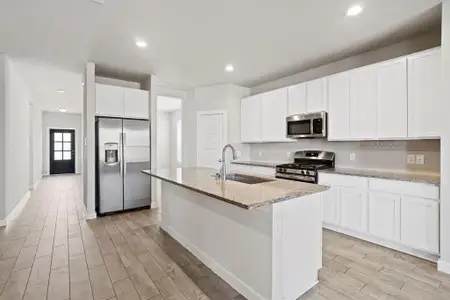 This spacious kitchen is a chef’s dream, featuring a large island, ample counter space, and high ceilings. It boasts sleek white cabinets, granite countertops, stainless steel appliances, a modern tile backsplash, a wide sink, and a walk-in pantry—all overlooking the living and dining areas for a seamless open-concept feel.