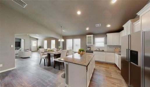 The open floor plan emphasizes the seamless flow between the kitchen, dining, and living areas. Large windows bathe the space in natural light, highlighting the elegant tile flooring and neutral wall colors. This layout is perfect for creating a versatile and inviting living environment. This is a picture of an Elise Floor Plan with another Saratoga Homes.