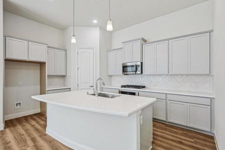 Kitchen with pendant lighting, sink, a kitchen island with sink, hardwood / wood-style flooring, and stainless steel appliances