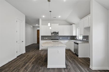 Kitchen with tasteful backsplash, appliances with stainless steel finishes, dark wood-type flooring, and a sink