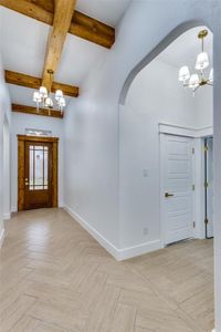 Foyer entrance featuring light parquet floors, an inviting chandelier, and beamed ceiling