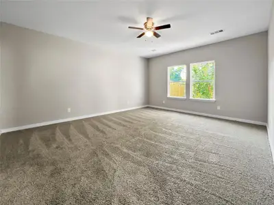 Carpeted empty room with ceiling fan and baseboards