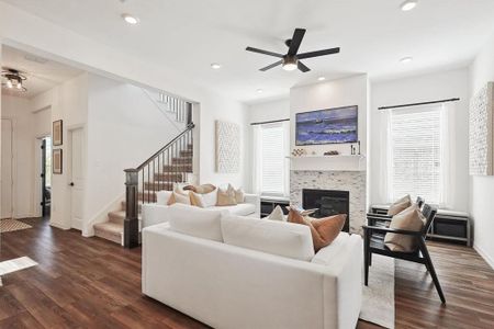 Living room featuring a fireplace, dark hardwood / wood-style flooring, and ceiling fan