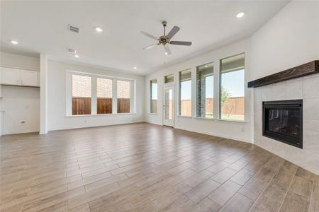 Unfurnished living room featuring ceiling fan, light wood-type flooring, and a tile fireplace