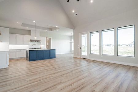 Example of builders Kitchen w vaulted ceiling, exhaust fan will be different, light wood-type flooring, and white cabinetry