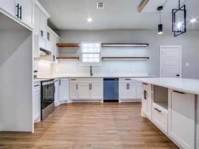 Kitchen featuring white cabinets, pendant lighting, light hardwood / wood-style floors, and appliances with stainless steel finishes