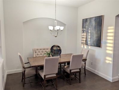 Dining area with dark wood-type flooring and a chandelier