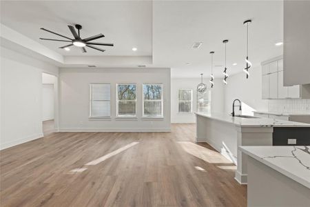 Kitchen with light wood-style floors, backsplash, modern cabinets, a raised ceiling, and pendant lighting