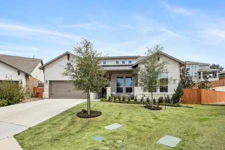 View of front facade featuring a front lawn, fence, driveway, and a standing seam roof