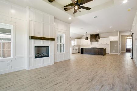 Unfurnished living room with light hardwood / wood-style floors, ceiling fan, a large fireplace, and a healthy amount of sunlight