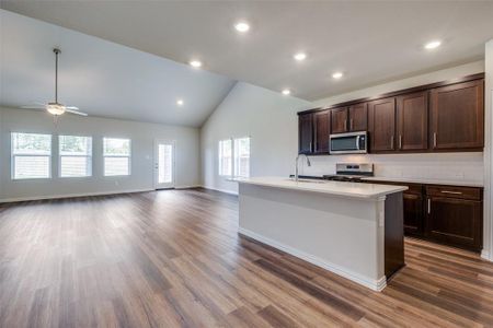 Kitchen featuring appliances with stainless steel finishes, tasteful backsplash, sink, a kitchen island with sink, and dark wood-type flooring