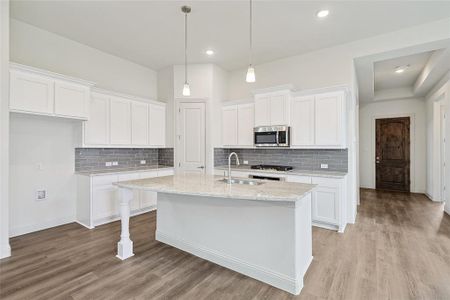 Kitchen with white cabinets, an island with sink, light hardwood / wood-style flooring, and sink