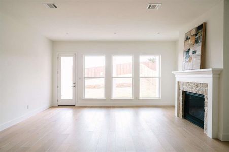 Unfurnished living room featuring light hardwood / wood-style floors and a stone fireplace