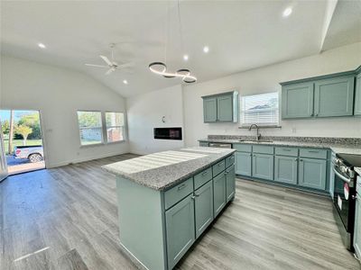 Kitchen featuring stainless steel range with electric stovetop, vaulted ceiling, plenty of natural light, and sink with disposal